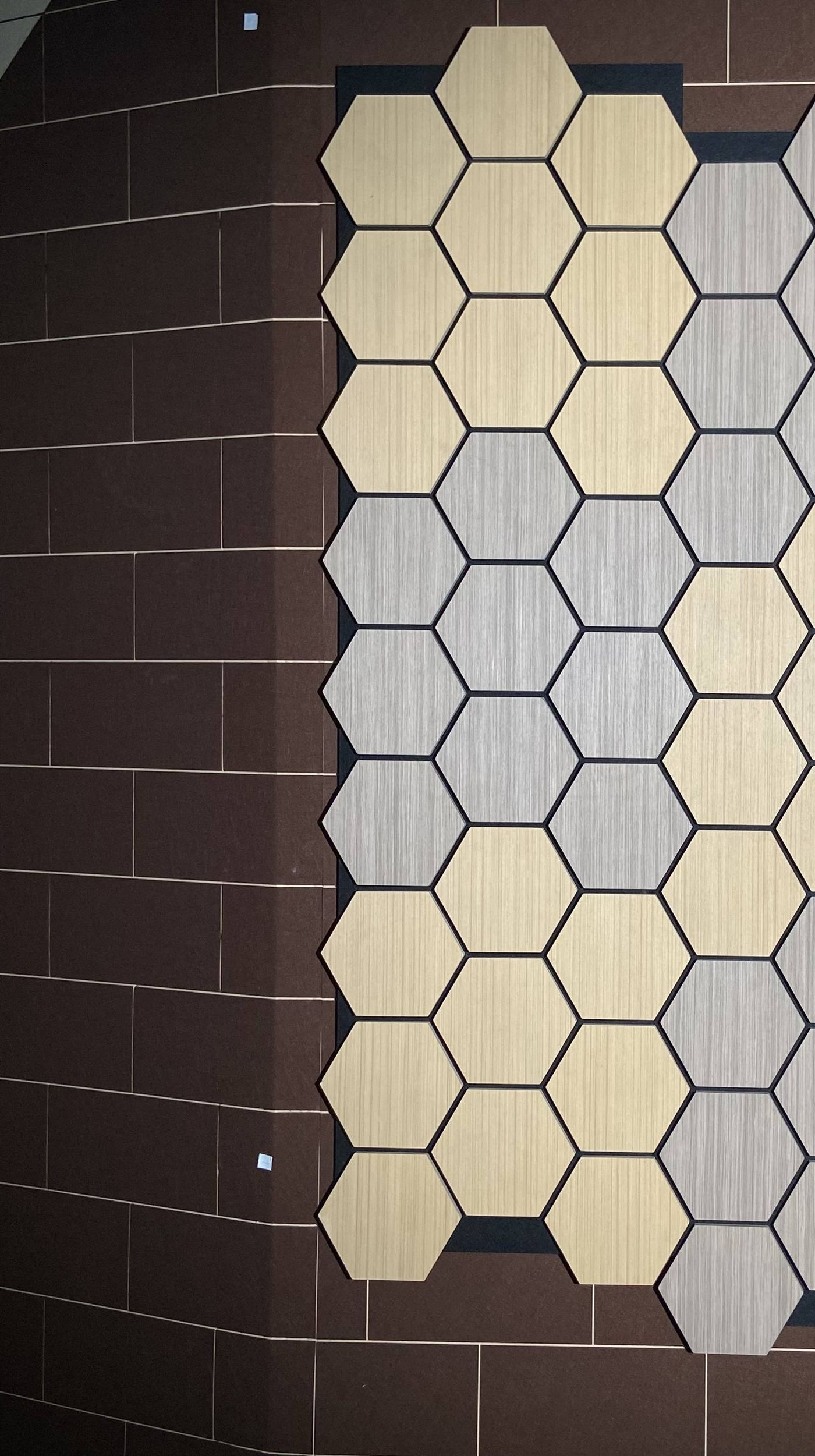 Muro de exposici&oacute;n con paneles hexagonales de madera en varios tonos