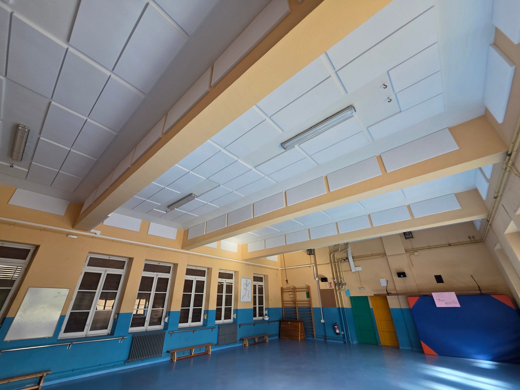 Gimnasio escolar con techo y frisos revestidos de paneles blancos de espuma t&eacute;cnica