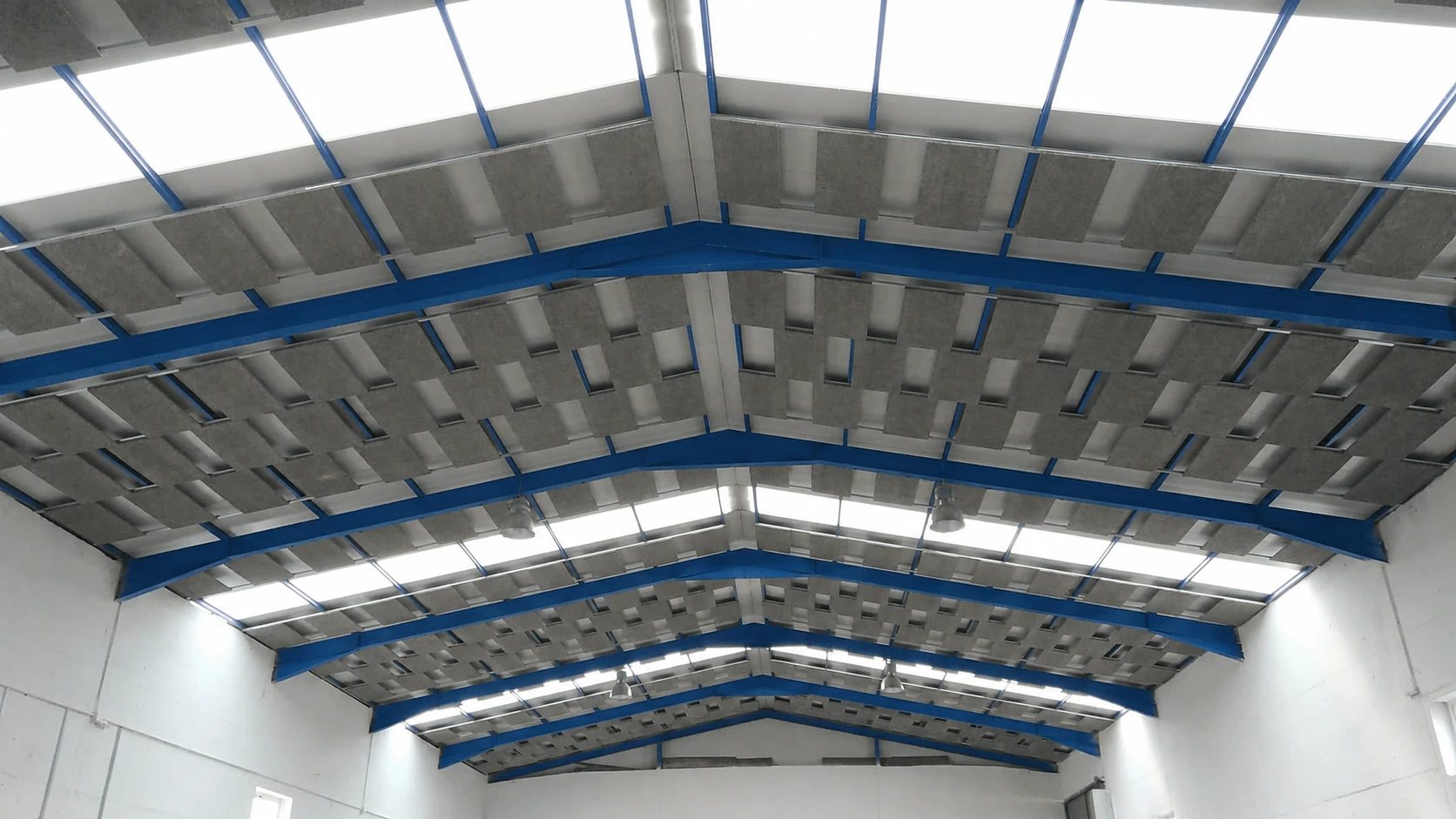 Nave industrial con paneles de fibra de madera suspendidos bajo la cubierta